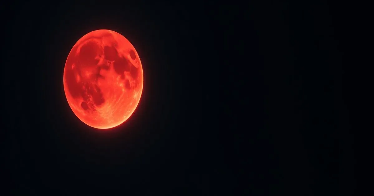 A striking, vibrant red full moon glows against a deep, dark, and minimalist black night sky.